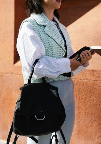 Modern fashion photo of a woman with a black bag and stylish outfit outdoors.